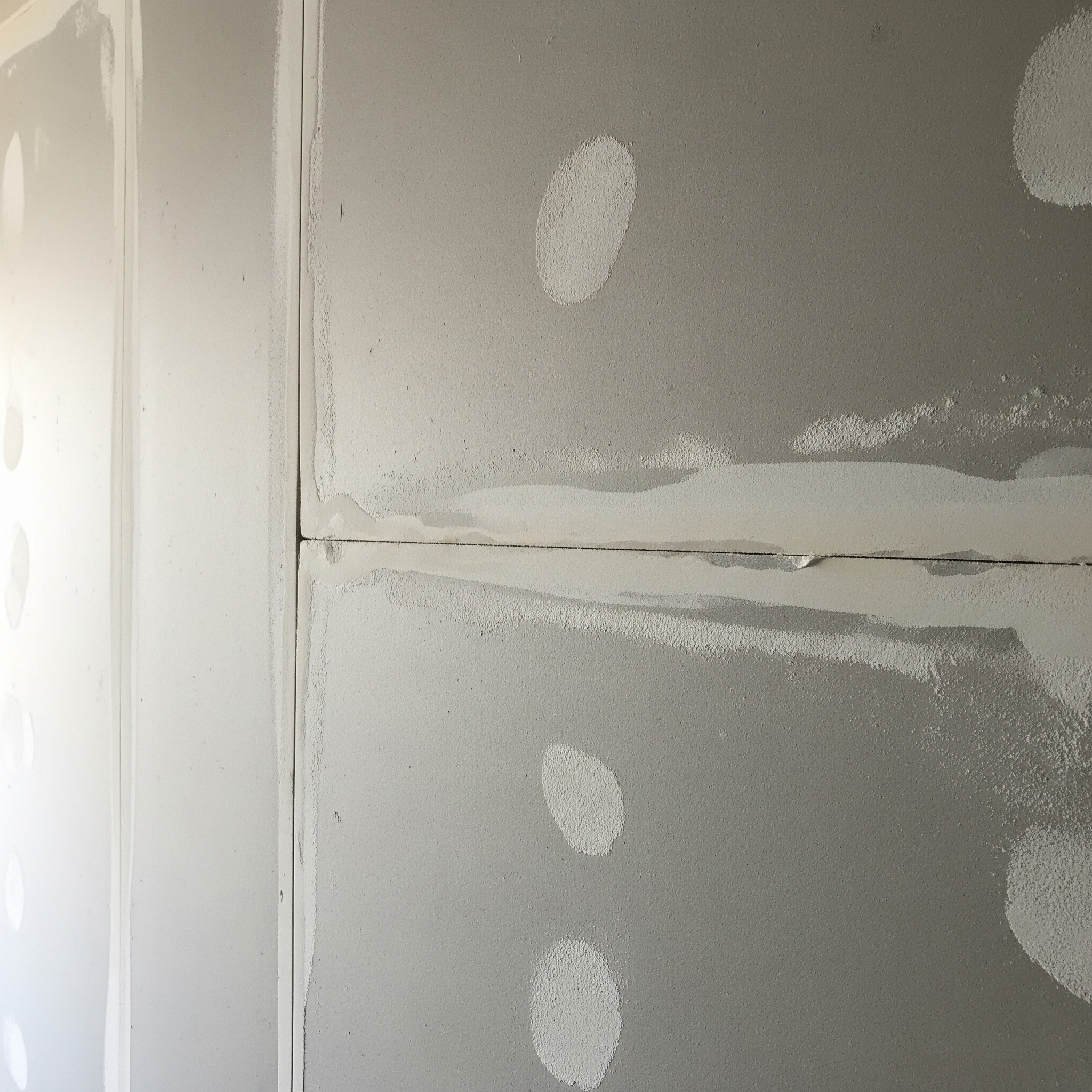 Before drywall finishing: A wall with rough taping and mudding.